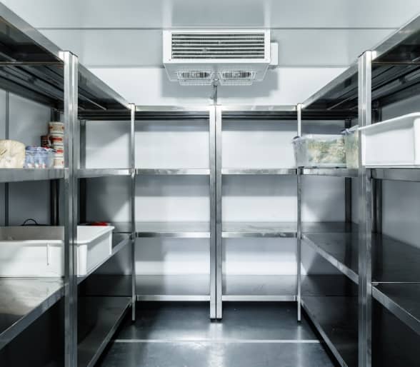 Photo d'intérieur d'une chambre froide avec des étagères en acier inoxydable contenant des bacs de nourriture